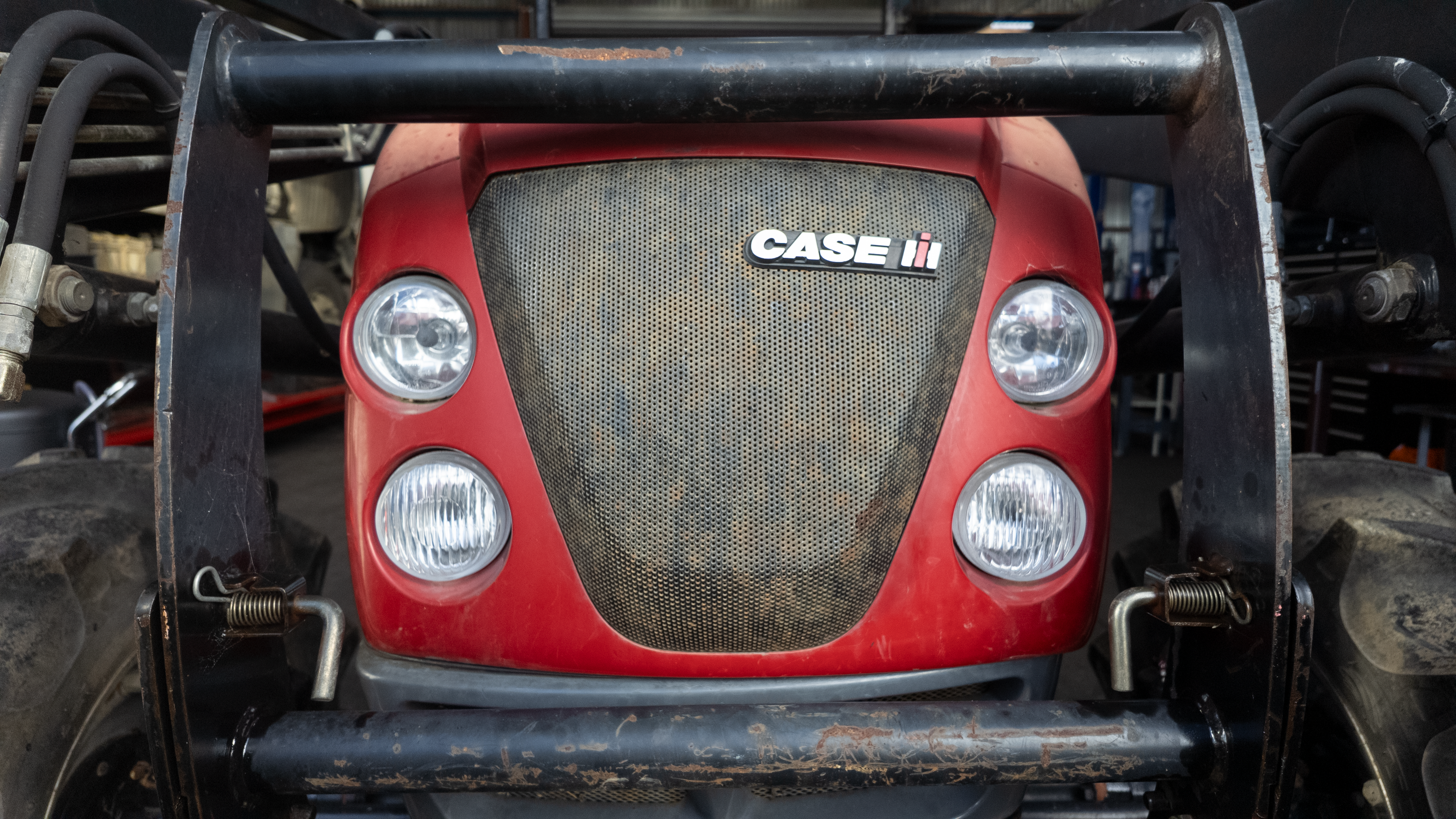 Close-up front view of a red Case IH tractor with a black front grille and protective bumper bars.